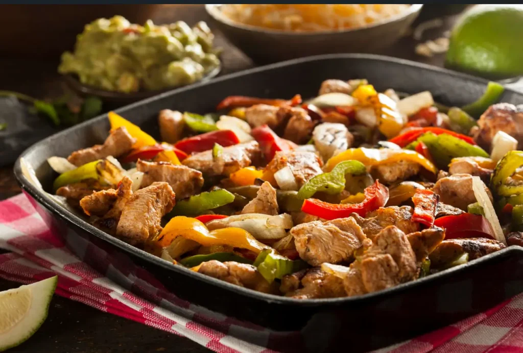 A serving of crockpot chicken fajitas served with flour tortillas and garnishes